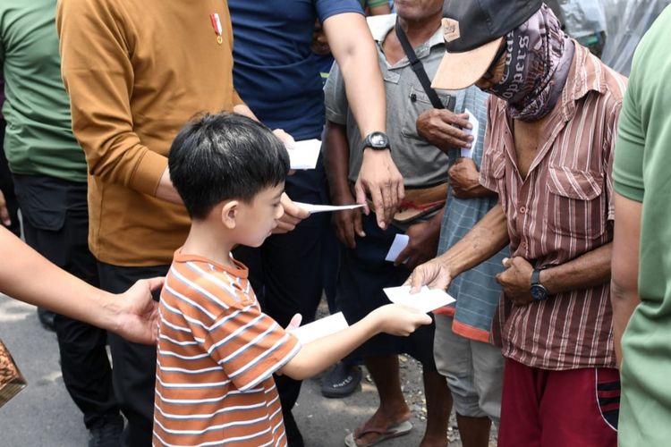 Presiden Joko Widodo dan cucunya Jan Ethes Sinarendra membagikan bantuan kepada warga Kota Solo, Jawa Tengah, Sabtu (8/4/2023).