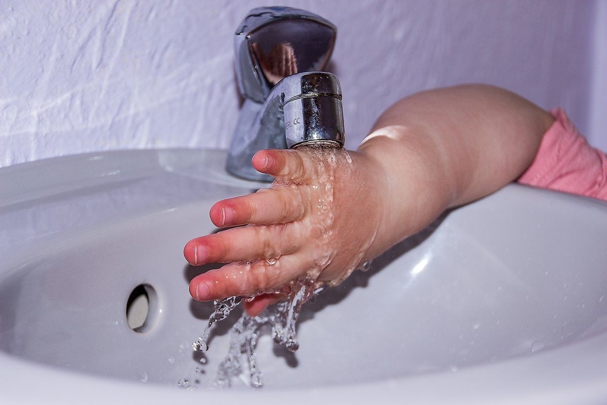 Ilustrasi balita sedang mencuci tangan dengan air mengalir.