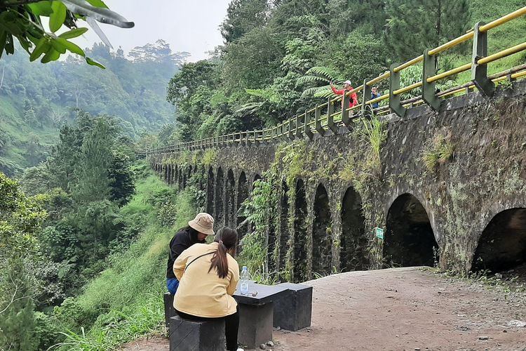 Dua wisatawan saat berwisata di Plunyon Kali Kuning. Tampak bangunan Jembatan Plunyon yang menjadi favorit wisatawan untuk berfoto.