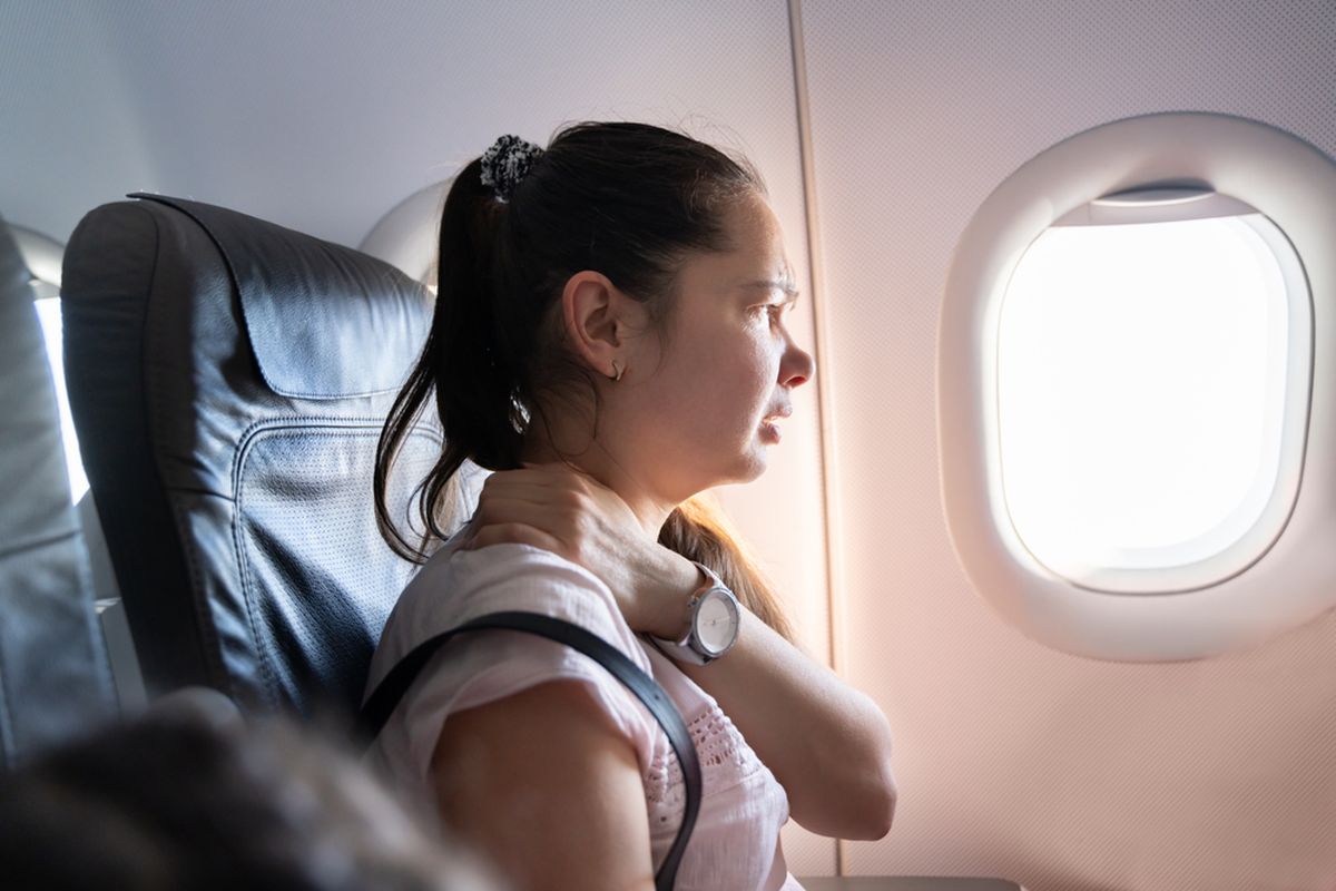 Ilustrasi penumpang pesawat dengan leher yang sakit.