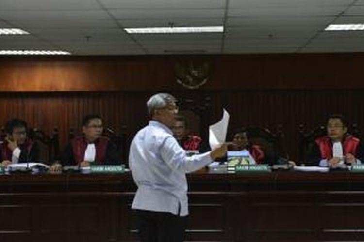 Mantan Ketua Mahkamah Konstitusi (MK) Akil Mochtar menunjukkan bukti saat menjalani pemeriksaan sebagai terdakwa dalam persidangan di Pengadilan Tindak Pidana Korupsi, Jakarta, Senin (2/6/2014). Akil didakwa karena diduga menerima suap dalam pengurusan sengketa pilkada di MK.  
 