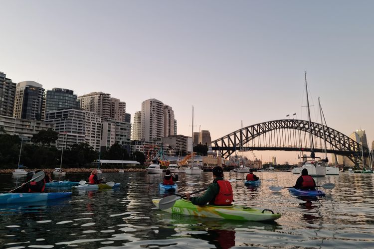 Kegiatan tur menikmati sunrise di Sydney Harbour dengan perahu kayak. Tur ini disediakan oleh Sydney by Kayak.