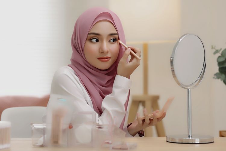 Ilustrasi seorang perempuan berhijab sedang makeup agar tampil dapat tampil lebih segar.