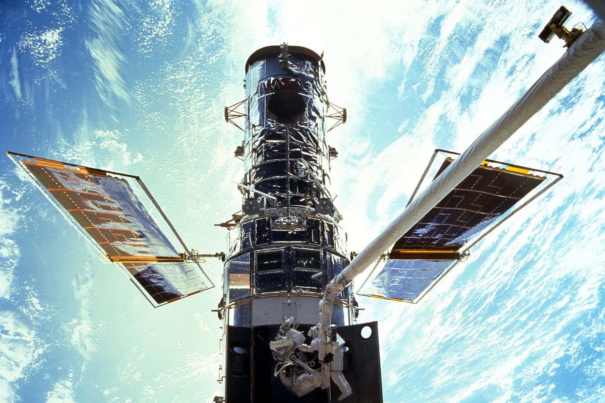Foto dari NASA/JSC memperlihatkan astronot Steven L Smith dan John M Grunsfeld saat extravehicular activity (EVA) di perawatan teleskop Hubble pada Desember 1999.