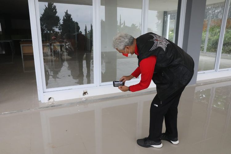 Gubernur Jawa Tengah Ganjar Pranowo sidak dadakan di pembangunan SMAN Tawangmangu, Kabupaten Karanganyar, saat menfoto tembok jebol, Minggu (30/1/2022).