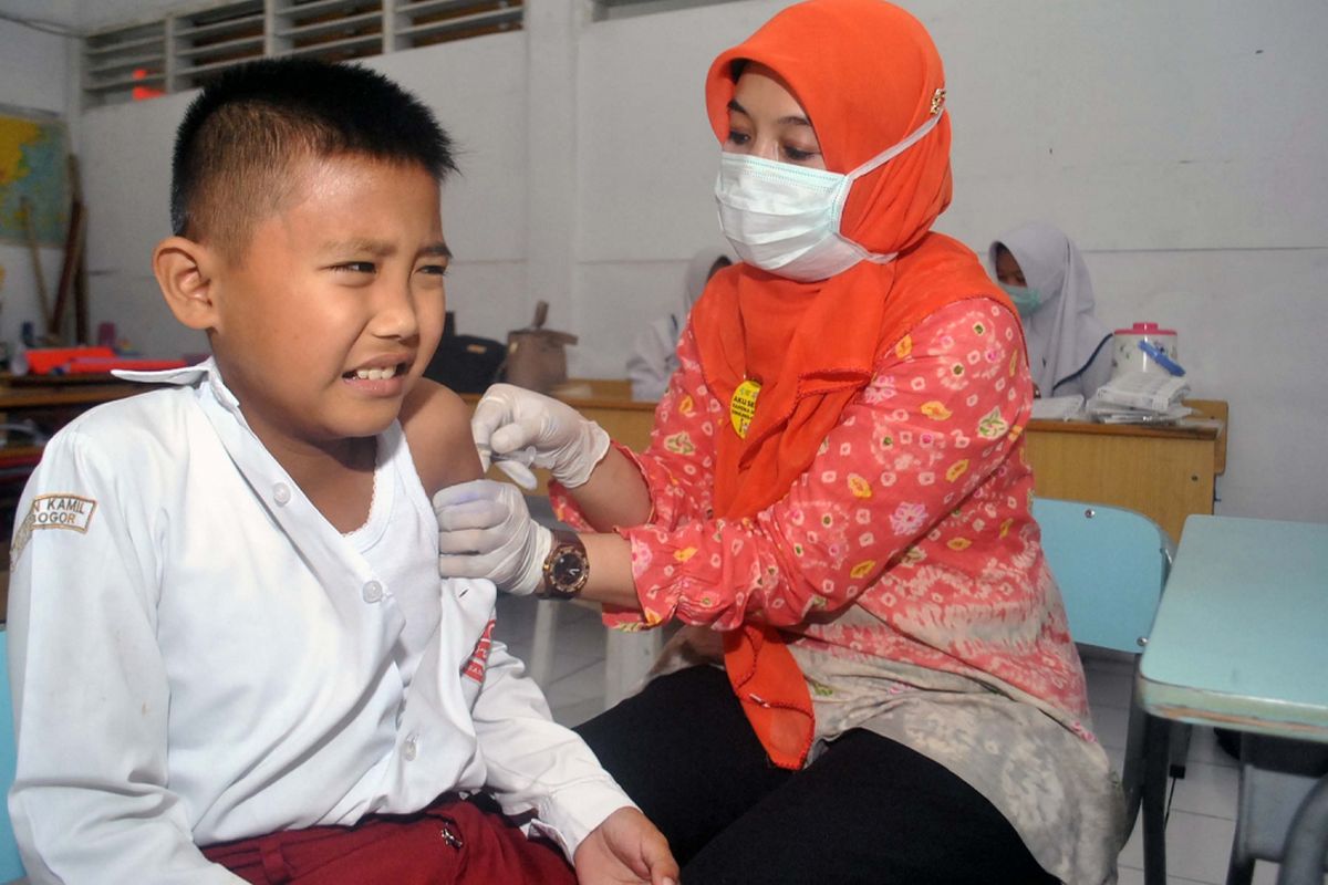 Petugas Puskesmas Sindangbarang Bogor memberikan imunisasi campak Measles Rubella kepada siswa di SD Insan Kamil, Kota Bogor, Jawa Barat, Rabu (9/8/2017). Pemberian imunisasi campak Rubella dilaksanakan dalam dua fase, yakni Agustus - September 2017 di seluruh wilayah Pulau Jawa dan pada Agustus - September 2018 di seluruh provinsi di luar pulau Jawa dengan target mencapai cakupan minimal 95 persen agar eliminasi campak dan pengendalian Rubella dapat terwujud pada 2020. ANTARA FOTO/Arif Firmansyah/ama/17