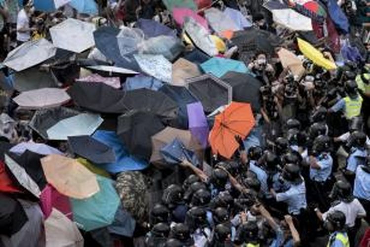 Para pengunjuk rasa pro-demokrasi Hongkong menggunakan payung mereka untuk menangkal serangan semprotan merica atau gas air mata yang dilepaskan aparat kepolisian.