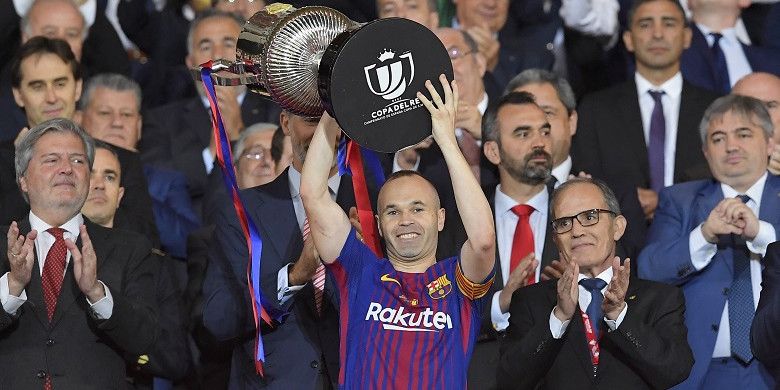 Kapten Barcelona, Andres Iniesta, mengangkat trofi juara Copa del Rey 2018 yang diraihnya pasca mengalahkan Sevilla 5-0 di Stadion Wanda Metropolitano, Madrid, pada Minggu (22/4/2018).
