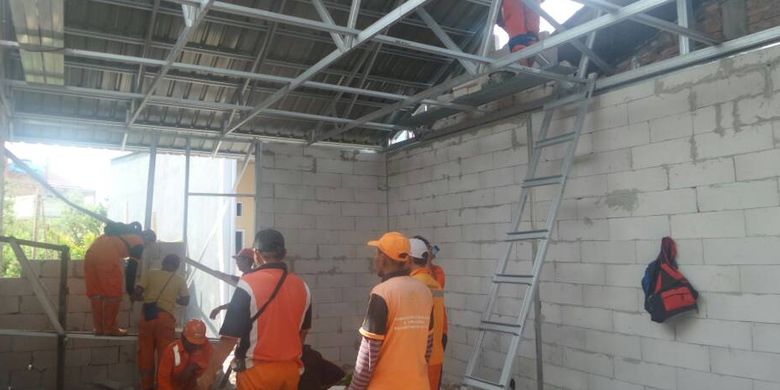 Pasukan merah dan petugas PPSU sedang melakukan pemasangan atap dan tembok di rumah-rumah yang termasuk dalam program bedah rumah yang dicanangkan Pemprov DKI Jakarta, Jumat (5/5/2017)