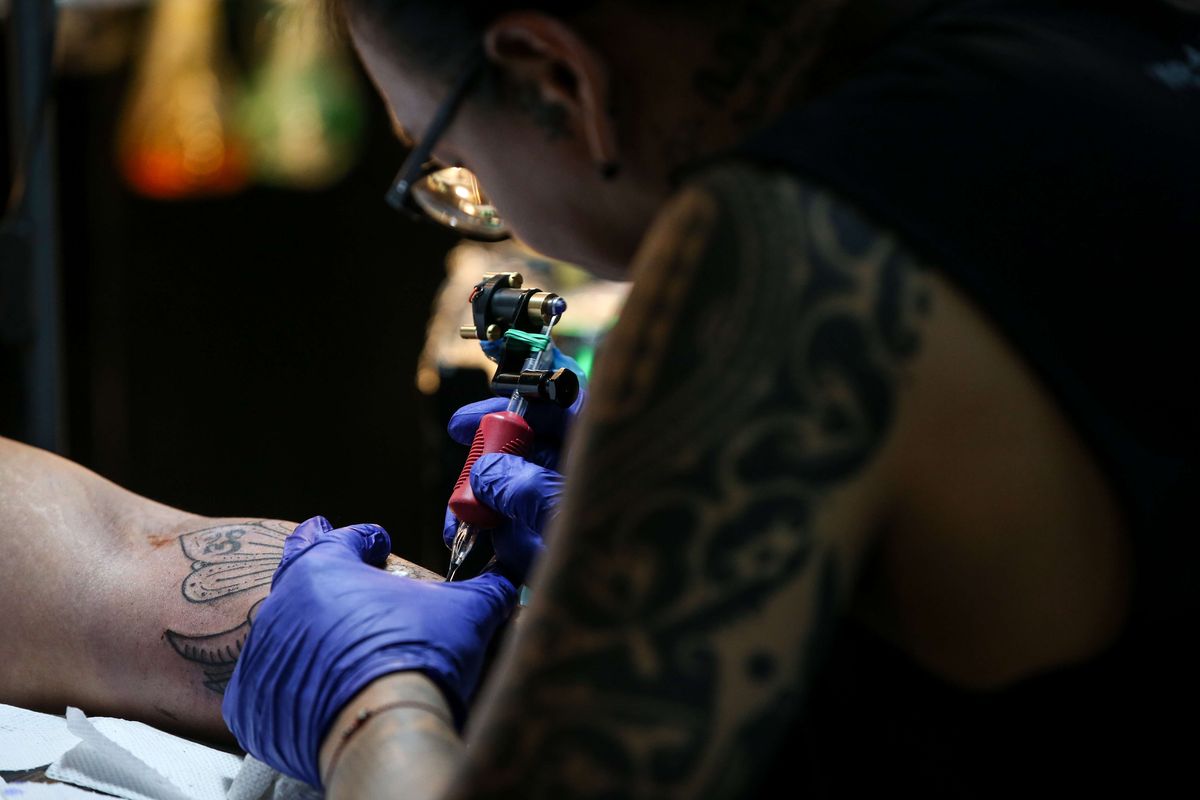 Seniman tato, Ade Itameda tengah menyelesaikan pembuatan tato saat acara live tattooing dan custom art painting bertajuk Ke Jakarta Vol. 2 di Ruang Selatan, Kemang, Jakarta Selatan, Sabtu (6/7/2019).