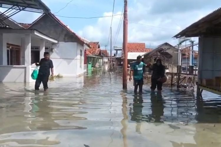 Warga saat melintas di banjir rob di Desa Saobi, Kecamatan Kangayan, Sumenep. 