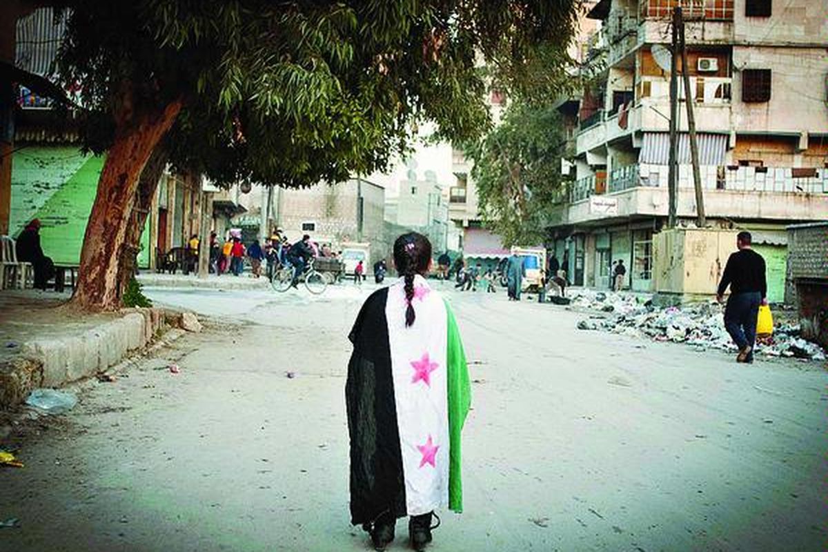 Seorang gadis berjalan di tengah kota Aleppo, Suriah, dengan berselimutkan bendera Suriah sebelum era kekuasaan Partai Baath yang kini menjadi bendera pasukan oposisi Tentara Pembebasan Suriah (FSA), Rabu (13/2). Pasukan oposisi hampir menguasai sepenuhnya sebuah pangkalan militer strategis di Suriah utara setelah pertempuran sengit dengan pasukan pemerintah.