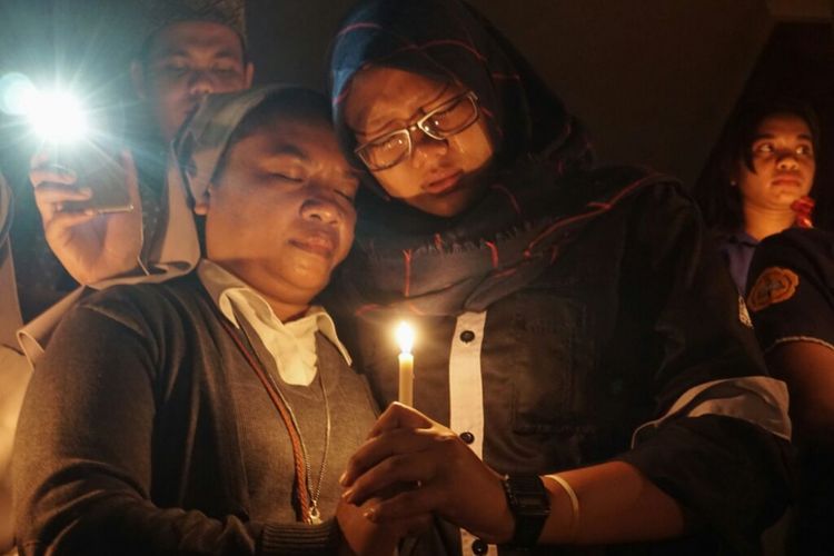 Jari Suster Lili dan jari Olivia Prisandra menyatu mengengam sebuah lilin yang menyala saat mengikuti acara doa lintas iman di depan Auditorium Driyarkara Universitas Sanata Dharma (USD),Yogyakarta.