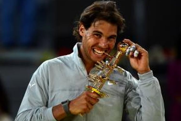 Petenis Spanyol Rafael Nadal menggigit trofi juara Mutua Madrid Open yang didapat setelah mengalahkan Kei Nishikori pada partai final, Minggu (11/5/2014). Nadal menang 2-6, 6-4, 3-0.  Nishikori mundur karena cedera pada pinggang.