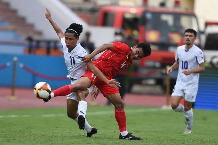 Pesepak bola Timnas Indonesia Asnawi Mangkualam Bahar (tengah) berebut bola dengan pesepak bola Timnas Filipina  Yrick Gallantes (kiri) saat bertanding dalam laga lanjutan Grup A Sepak Bola SEA Games 2021 Vietnam di Stadion Viet Tri, Phu Tho, Vietnam, Jumat (13/5/2022). . Indonesa menang atas Filipina dengan skor 4-0.