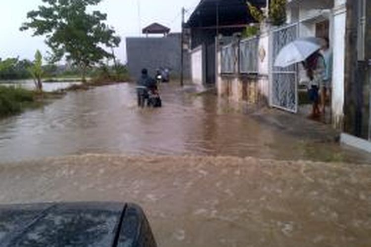 Warga mendorong motornya di jalan desa Lemper karena terendam banjir, Sabtu (4/1/2013).