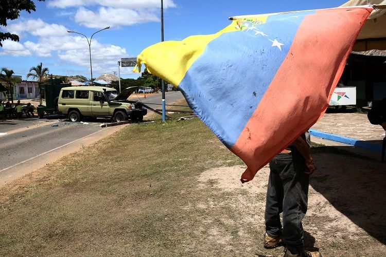 Foto ini memperlihatkan bendera Venezuela terlihat di lokasi  tentara Venezuela menembaki penduduk dekat perbatasan dengan Brasil di Kumarakapay, Venezuela, 22 Februari 2019. (REUTERS/William Urdaneta)