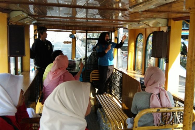 Laras (19) pemandu wisata bus Bandros saat melayani para wisatawan, Jumat (10/8/2018)