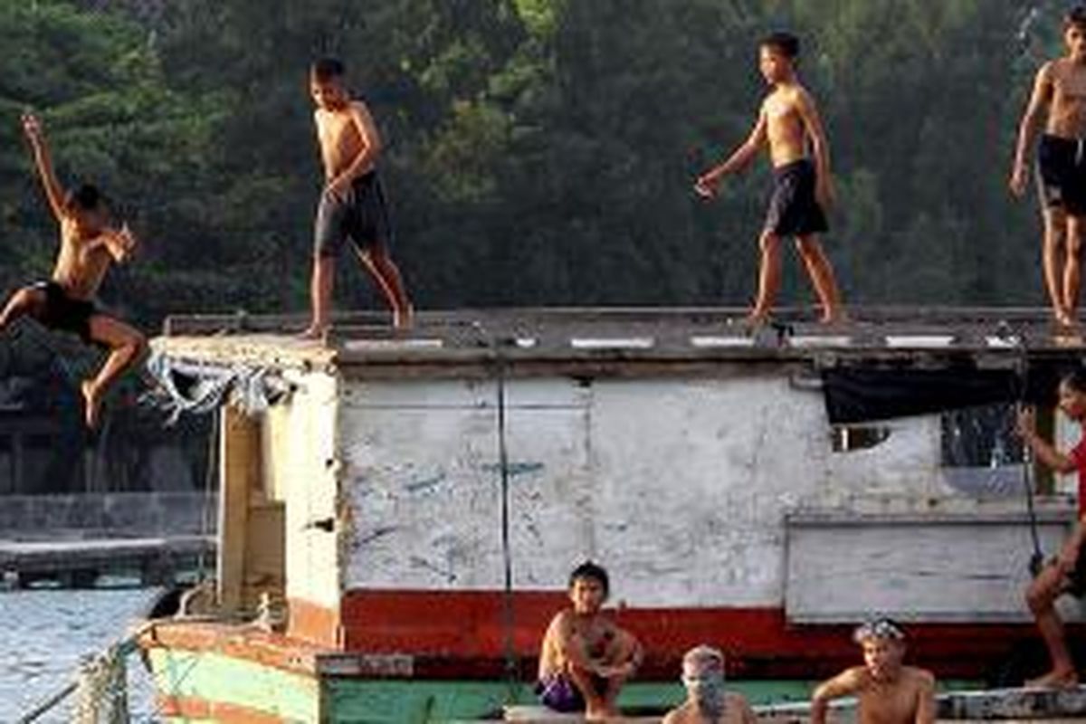 Anak-anak nelayan di Pulau Panggang, Kepulauan Seribu, Kamis (11/6/2015), bermain di atas perahu dan kapal yang tertambat di dekat dermaga. Suasana riang dan guyub seperti ini menawarkan sensasi tersendiri bagi pengunjung Pulau Panggang.