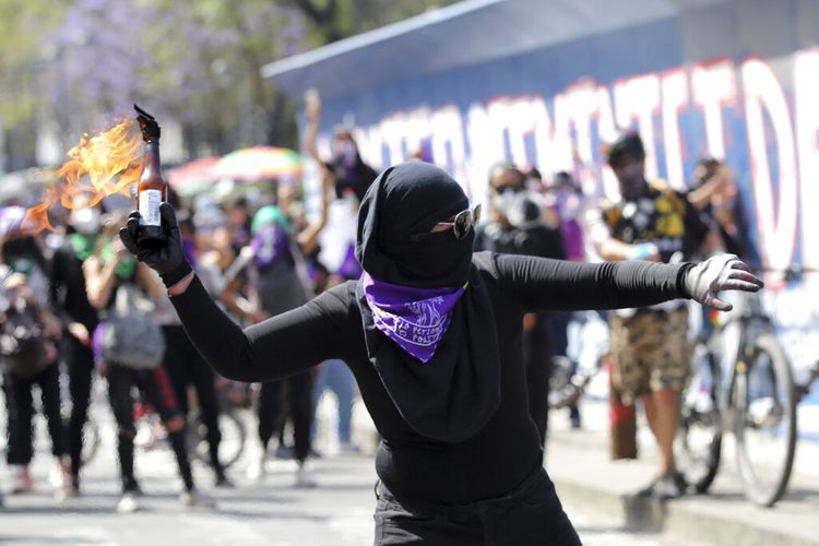 Seorang wanita bersiap-siap melemparkan bom bensin saat pawai memperingati Hari Perempuan Internasional dan memprotes kekerasan gender, di Mexico City, Senin (8/3/2021).