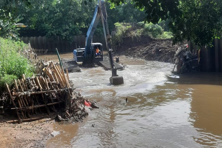 Excavator amphibi mengeruk tanah yang sudah dibebaskan untuk pembangunan sheet pile atau turap di pinggir Kali Angke wilayah Kembangan Utara, Kembangan, Jakarta Barat.