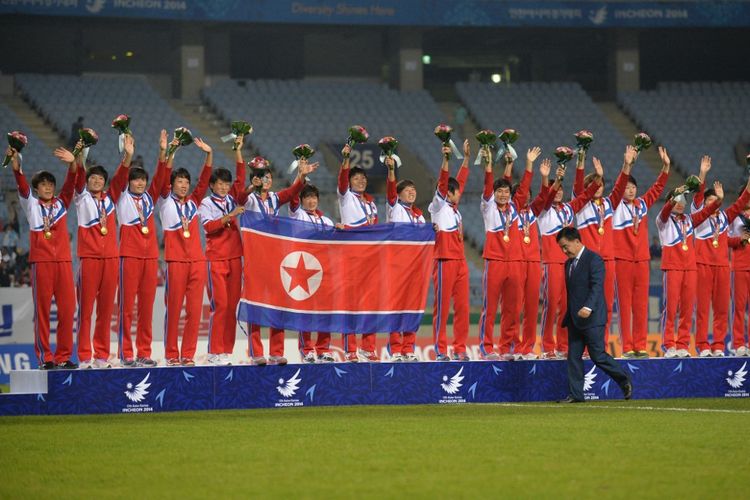 Timnas wanita Korea Utara berpose dengan membawa bendera negara mereka setelah menang di laga medali emas lawan Jepang di Stadion Munhak pada Asian Games 2014 di Incheon, 1 Oktober 2014.