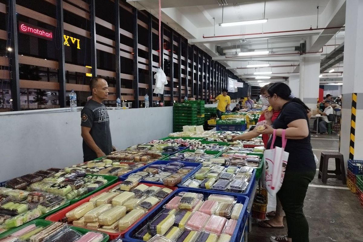 Pedagang kue bolu bernama Aswin (45) yang sedang melayani pelanggannya di Pasar Kue Subuh Senen, Jakarta Pusat, pada Jumat (24/3/2023). (KOMPAS.com/XENA OLIVIA)