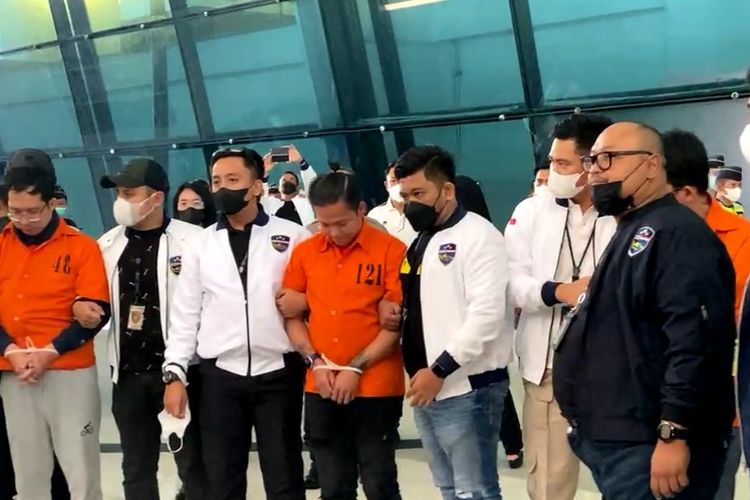 Tiga buronan judi online (menggunakan baju tahanan oranye) tiba di Bandara Internasional Soekarno-Hatta setelah ditangkap di Kamboja oleh Mabes Polri, Sabtu (15/10/2022).