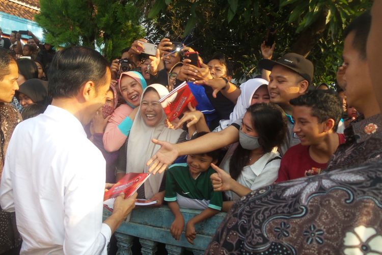 Presiden Joko Widodo sedang membagi-bagikan buku tulis kepada masyarakat Ciamis, Jawa Barat, Sabtu (10/6/2017). Di halaman Kantor Kepala Desa Sindangkasih itu, Jokowi sekaligus meninjau pembagian paket sembako bagi rakyat kecil.
