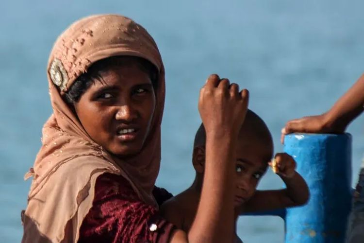 Seorang wanita Rohingya terlihat bersama anaknya di atas kapal yang terdampar sejauh satu kilometer dari pantai di Kabupaten Aceh Utara pada 2020.