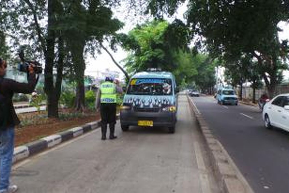 Petugas polisi lalu lintas mencegat sebuah angkutan umum yang masuk di Jalur Transjakarta, Jalan Raya Bekasi Timur, depan Rutan Cipinang, Jatinegara, Jakarta Timur. Razia tersebut melibatkan belasan petugas. Selasa (12/11/2013). 