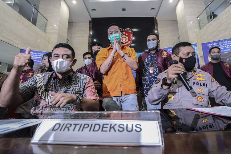 Dirtipideksus Bareskrim Polri Brigjen Whisnu Hermawan (kiri) bersama Kabag Penum Divisi Humas Polri Kombes Pol Gatot Repli Handoko (kanan) memberikan keterangan kepada media saat gelar barang bukti kasus afiliator Binomo dengan Tersangka Indra Kesuma atau Indra Kenz (tengah) di Bareskrim, Mabes Polri, Jumat (25/3/2022). Dalam acara tersebut petugas kepolisian menghadirkan sejumlah barang bukti berupa uang sejumlah Rp1,24 miliar serta mobil Tesla Model 3.