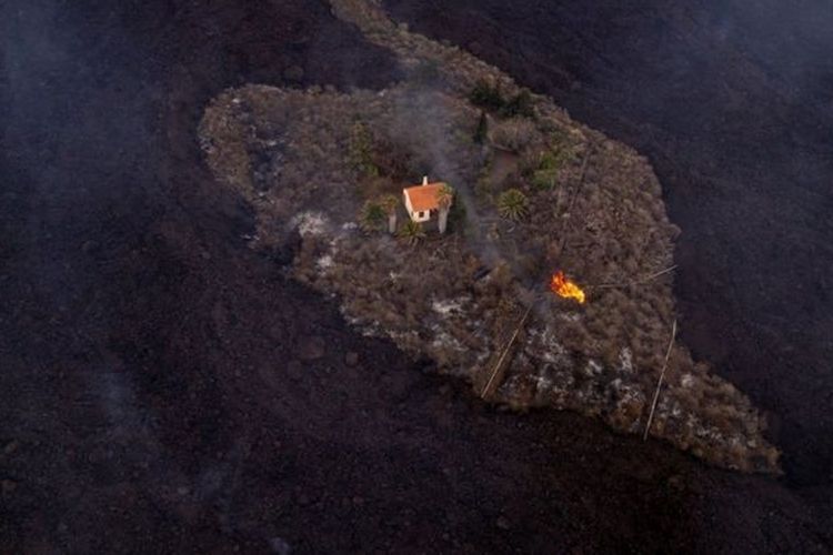 Foto yang diambil dari udara menunjukkan sebuah rumah yang masih berdiri meski di sekelilingnya hangus terkena aliran lava dari letusan Gunung Cumbre Vieja di La Palma, Spanyol.