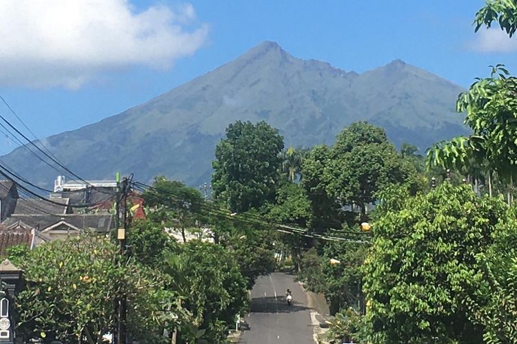 Warga melintas di salah satu ruas jalan di Kota Salatiga, Jawa Tengah, dengan latar lereng utara Gunung Merbabu, Selasa (24/5/2022).