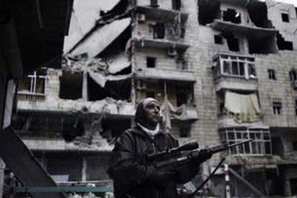 Guevara membawa senapannya bergerak di antara reruntuhan bangunan di kota Allepo, Suriah.