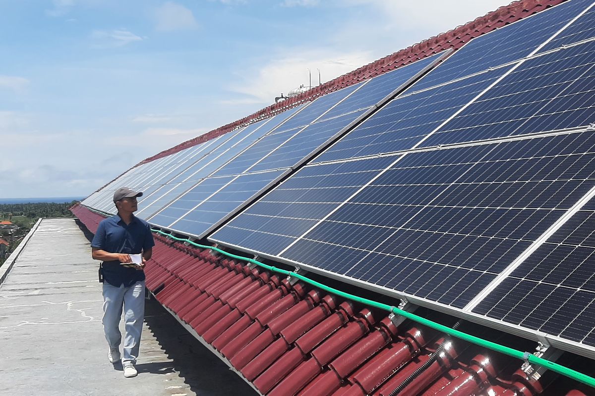 Seorang staf memeriksa kondisi panel surya di atap Hotel Santika Banyuwangi, yang berlokasi di Kelurahan Sobo, Kecamatan/Kabupaten Banyuwangi, yang mulai memanfaatkan energi baru terbarukan, Rabu (28/12/2022).