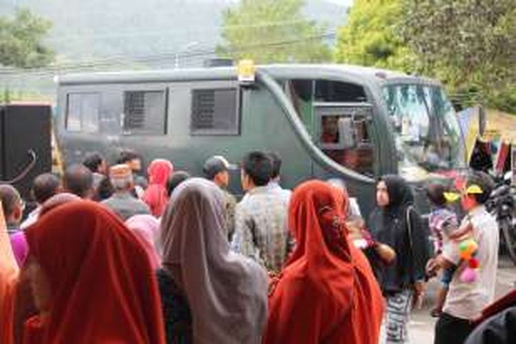 Sejumlah orangtua siswa PAUD/ TK Al Hikmah berdiri menyaksikan mobil tahanan milik Kejari Takengon meninggalkan lokasi eksekusi cambuk, tepat dihalaman Gedung Olah Seni (GOS) Takengon. Mobil itu diduga membawa para terdakwa pelanggar syariat islam yang akan di eksekusi cambuk di lokasi tersebut. Sementara pada pagi itu ruangan GOS digunakan oleh PAUD/ TK Al Hikmah untuk melaksanakan perpisahan dan pelepasan siswanya.