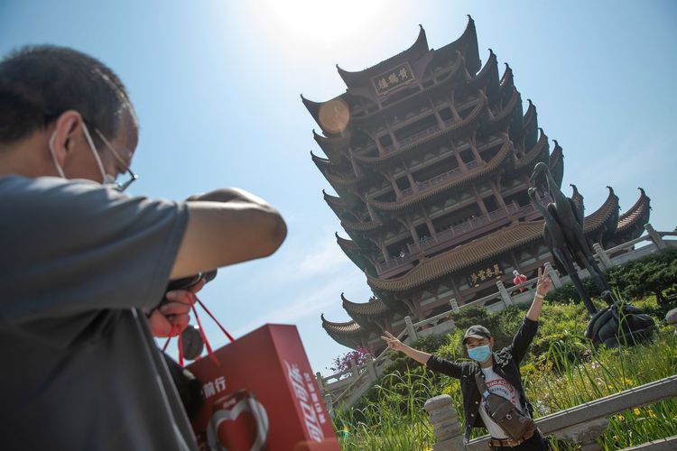 Pengunjung berpose di depan Yellow Crane Tower setelah kawasan tersebut kembali dibuka bagi publik, di Wuhan, Provinsi Hubeo, 29 April 2020. Setelah sempat menjalani masa karantina akibat penyebaran Covid-19, jutaan orang di China kembali turun ke jalan dan mengunjungi kawasan wisata yang kembali dibuka.