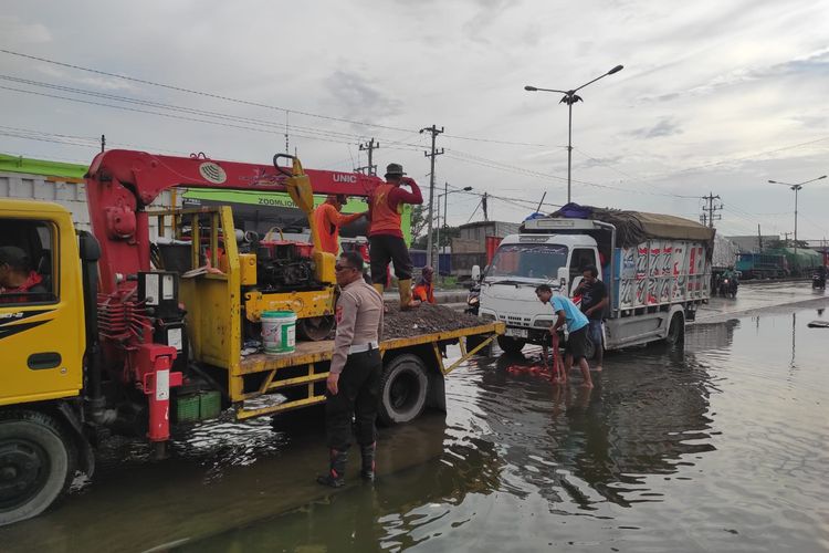 Mobil derek mengevakuasi truk yang alami kemogokan setelah menerjang banjir di Pantura Sayung, Kabupaten Demak, Jawa Tengah, Rabu (29/10/2025).