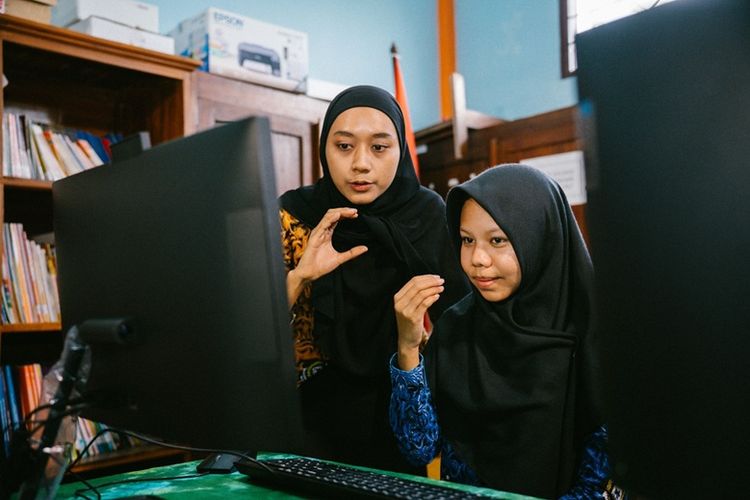 Siswa dan Guru sedang menggunakan perangkat komputer dari program AND. 