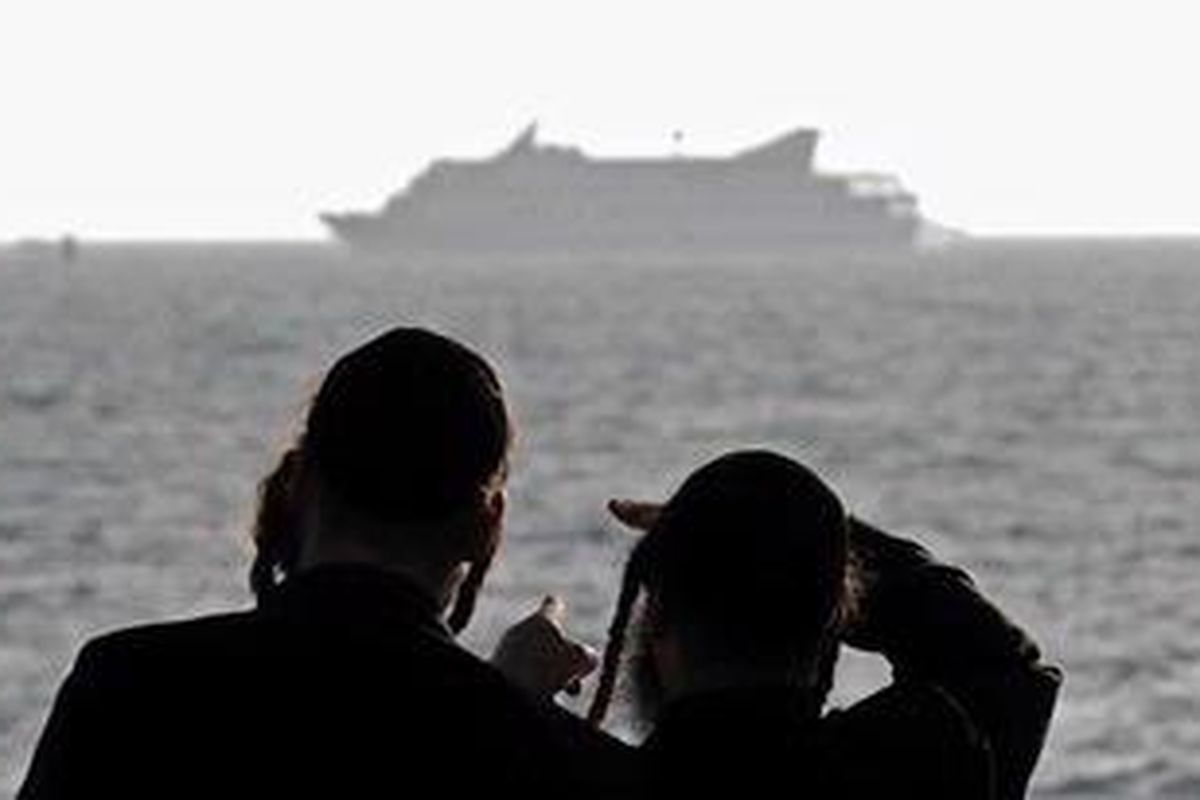 Dua warga Israel menyaksikan kapal bantuan kemanusiaan asal Turki, Mavi Marmara di lepas pantai sebelah selatan Israel. Pemandangan ini diambil usai penyerangan yang dilakukan pasukan Israel di atas geladak kapal itu, kemarin (Senin WIB, 31/5/2010).