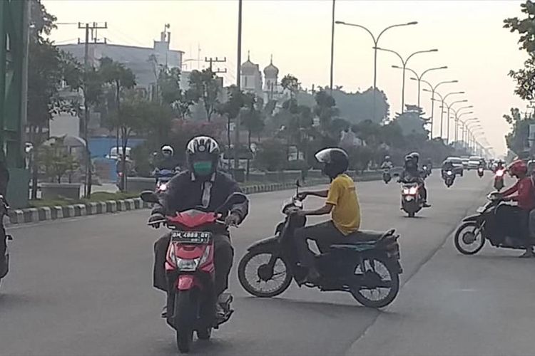 Kabut asap karhutla tampak menyelimuti ruas Jalan HR Soebrantas, Kecamatan Tampan, Kota Pekanbaru, Riau, Selasa (30/7/2019). Salah seorang pengendara terlihat mengenakan masker.