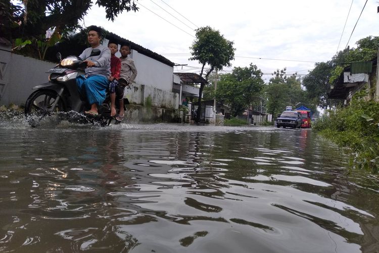 Warga nekat menerjang genangan air di Jalan A Yani Desa Cengkok, Ngronggot, Nganjuk, Selasa (9/3/2021).