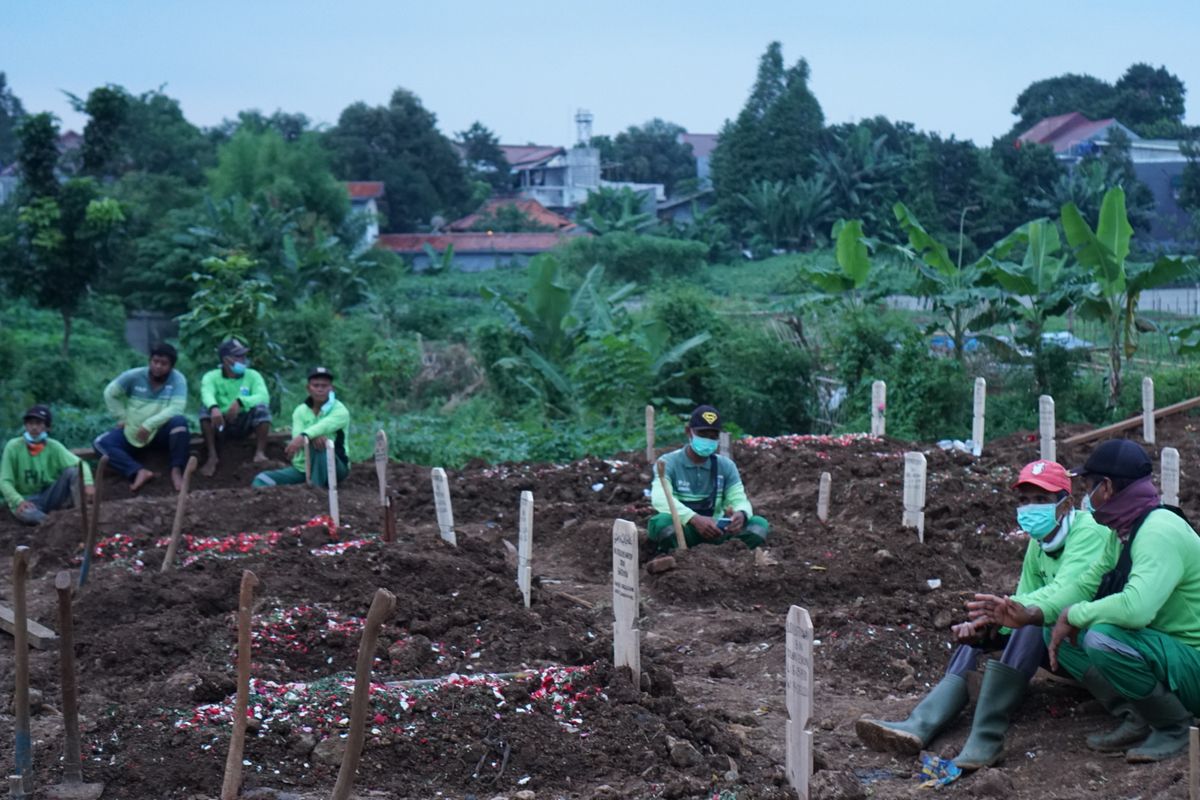 Para penggali kubur menunggu giliran untuk memakamkan peti jenazah pasien Covid-19 di Taman Pemakaman Umum (TPU) Srengseng Sawah, Jagakarsa, Jakarta Selatan pada Jumat (15/1/2021). TPU Srengseng Sawah dijadikan sebagai tempat pemakaman jenazah pasien Covid-19 sejak Selasa (12/1/2021). TPU Srengseng Sawah memiliki lahan seluas 0,5 hektar dan bisa menampung sekitar 700 makam untuk jenazah pasien Covid-19.