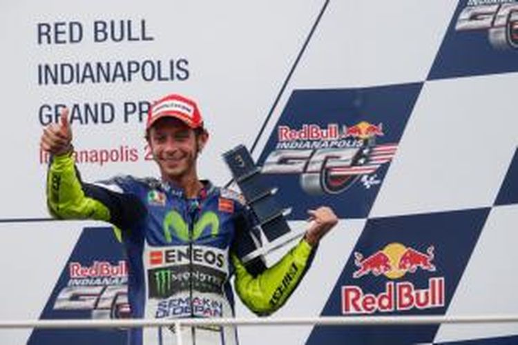 Pebalap Movistar Yamaha asal Italia, Valentino Rossi, mengangkat trofi hasil finis ketiga pada GP Indianapolis di atas podium Sirkuit Indianapolis Motor Speedway, Minggu (9/8/2015).