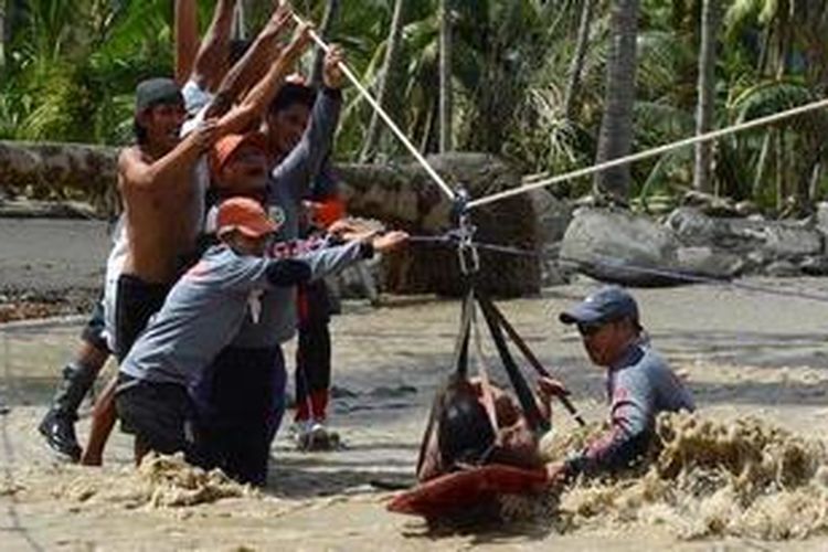 Dengan peralatan seadanya, para petugas penyelamat memindahkan korban selamat keluar dari kota New Bataan melalui sungai.