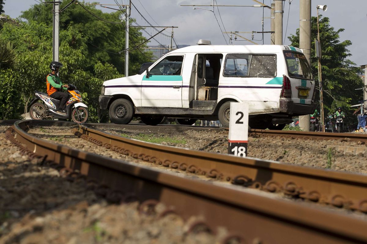 Mikrolet melintas di perlintasan kereta api wilayah Bumi Bintaro Permai, Pondok Aren, Jakarta Selatan, Minggu (23/2/2020). Tidak berfungsinya palang pintu di perlintasan kereta api sejak 2 tahun lalu mengancam keselamatan warga.