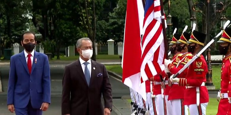 Screen grab of Malaysia's Prime Minister Muhyiddin Yassin (right) inspecting the guard of honor at Merdeka Palace in Jakarta during his state visit to Indonesia on Friday February 5, 2021. Accompanying him is Indonesia's President Joko Widodo (left).  