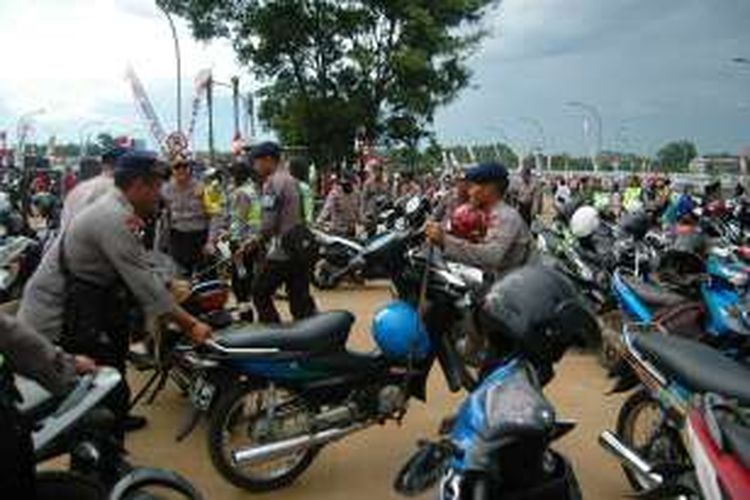 Sejumlah petugas kepolisian sedang mengangkut motor yang parkir sembarangan di depan pintu masuk VVIP Stadion Pakansari, Rabu (14/12/2016).