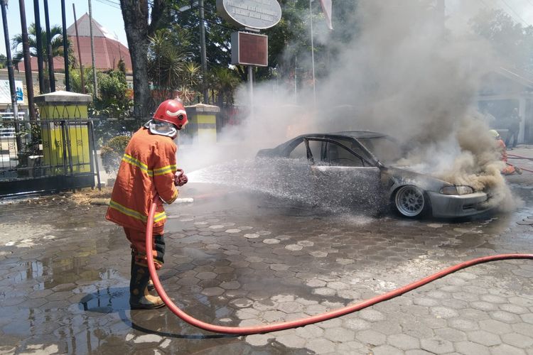 Petugas memadamkan api yang membakar sebuah mobil yang terparkir di Wisma UKSW Salatiga